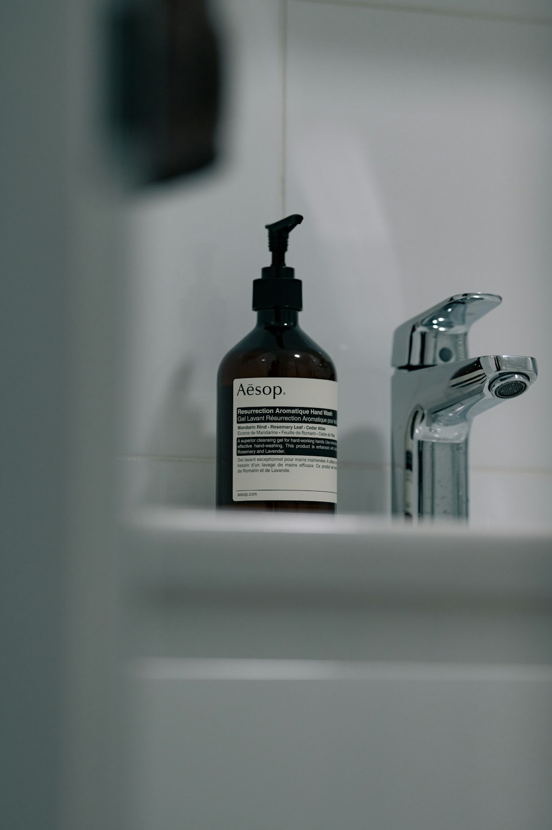 aesop-hand-soap-bottle-next-to-a-chrome-faucet-lswyprnfh0s